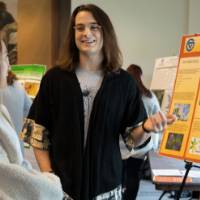 A group of students smile during a poster presentation